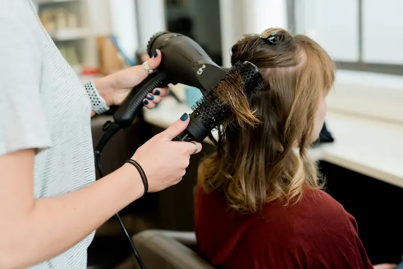 Coiffeuse réalisant un brushing à la brosse ronde