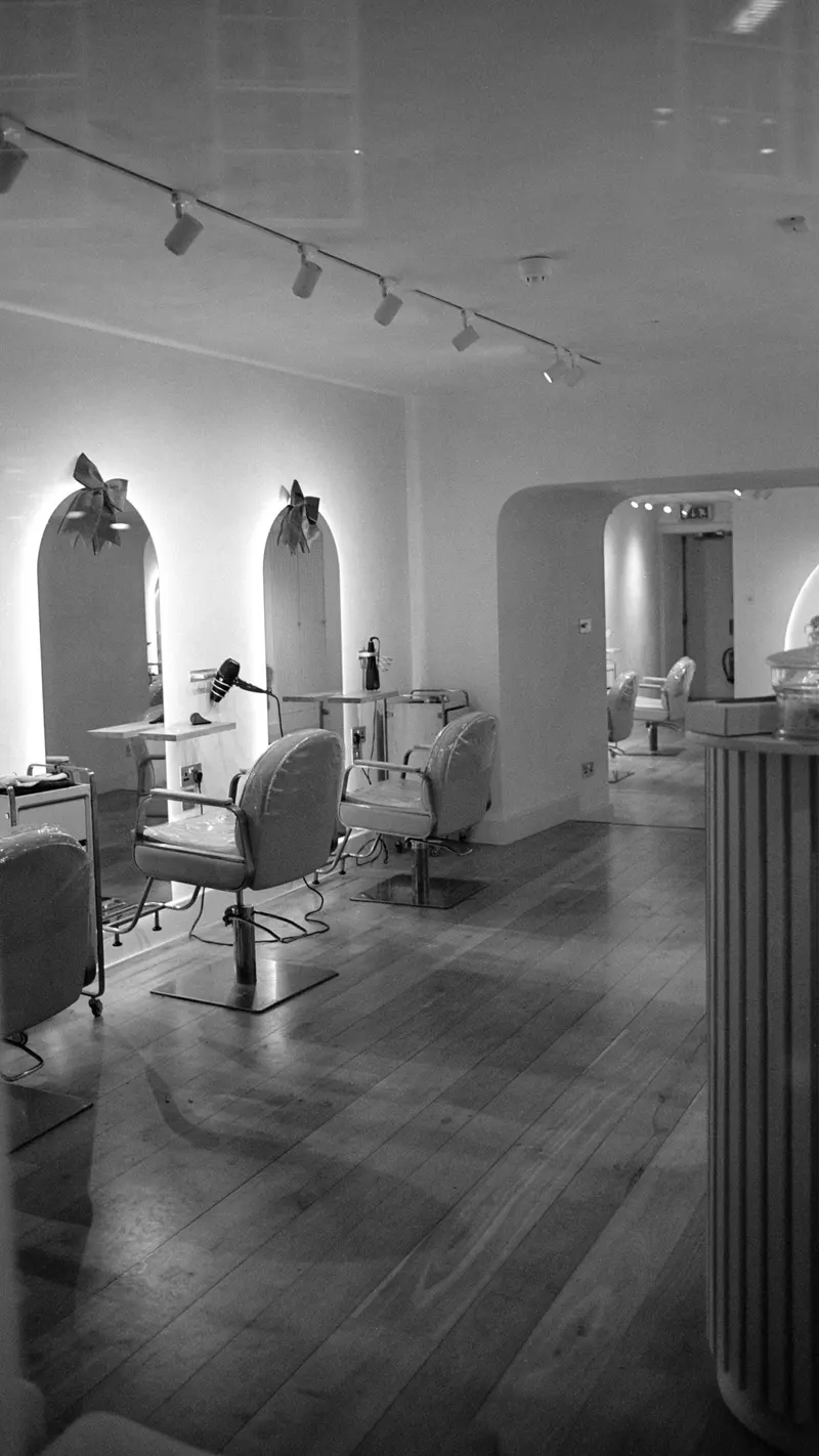 Intérieur d’un salon de coiffure avec fauteuils, miroirs en arche et lumière douce