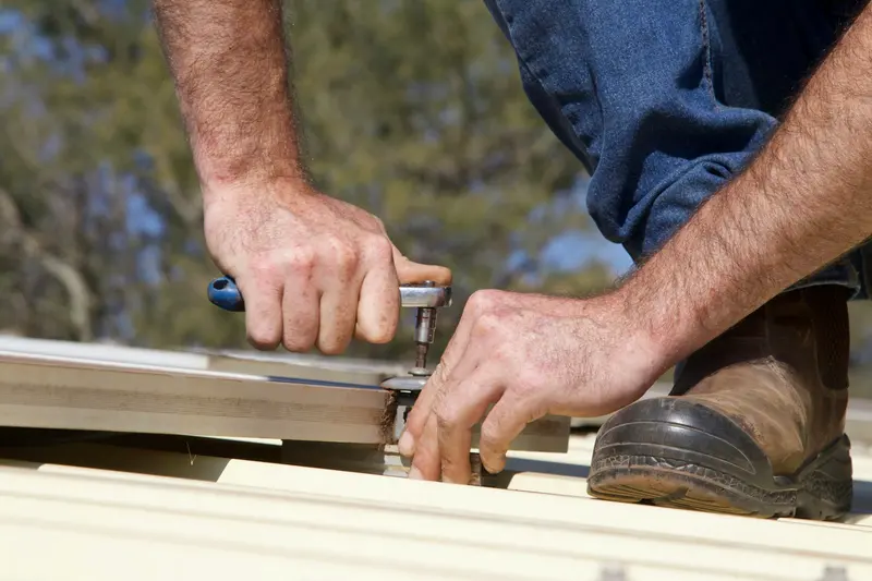 Mains fixant une couverture métallique avec un outil