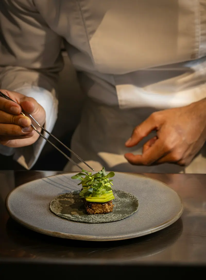 Chef dressant une assiette avec une pince