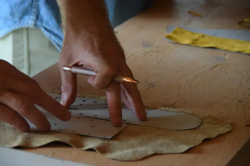Mains traçant un patron sur une pièce de cuir