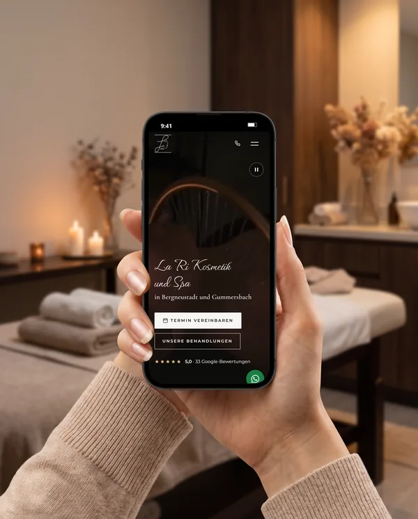 Main tenant un téléphone qui affiche le site de l’institut La Ri Kosmetik und Spa, réalisé par notre équipe, dans une cabine de soins éclairée aux bougies